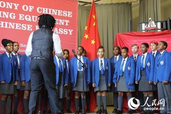 　　3月6日，中国驻南非大使馆向南非豪登省10所中小学捐赠汉语教材和课外读物。南非学生在捐赠仪式上合唱改编自《北京欢迎你》的《南非欢迎你》。  　　中国驻南非大使馆6日向南非豪登省10所中小学捐赠汉语教学设备。中国驻南非大使田学军、南非基础教育部长莫采卡，以及当地10所汉语教学试点中小学的校长和师生代表出席了活动。  　　2016年以来，汉语教学试点在这10所中小学顺利启动。继南非后，毛里求斯、坦桑尼亚、喀麦隆、赞比亚等非洲国家纷纷将汉语纳入了所在国家的国民教育体系，非洲大陆的“汉语热”正在持续升温。  　　2015年3月，南非政府宣布将汉语纳入国民教育体系。中国政府随后采取了一系列举措支持汉语教学试点工作：安排专家协助南非基础教育部编写了汉语教学大纲;向试点学校选派了经验丰富的汉语教师和志愿者;提供了2000册教材并配备了相应的教学设备;同时协助南非基础教育部培训本土汉语教师。  　　中国驻南非大使田学军表示，南非的汉语教学将对非洲各国具有重要的引领和示范作用。中方愿继续根据南方的实际需要，进一步加大汉语教师和志愿者的派遣规模，进一步加大对本土汉语教师的培养力度，并同南非基础教育部积极探讨合作编写更适合南非中小学生的汉语教材。  　　田学军透露，中南高级别人文交流机制即将正式启动，这也是中国同非洲国家建立的首个人文交流机制。该机制将在两国人文领域发挥顶层设计、重点规划和推动落实的作用，使中南关系的民意基础更加坚实，使人文领域的交流合作更多造福两国人民。  　　南非基础教育部长莫采卡感谢中方对南非教育事业发展的大力支持。她表示，在全球化盛行的当今社会，掌握一门外语即打开一扇通往新世界的大门。中国在基础教育领域的成功经验和做法值得南非借鉴，希望双方未来加强沟通对话，进一步拓展合作领域，力争取得更多合作成果。  　　当天，威罗瑞吉中学汉语班的学生们用中文演唱了改编自《北京欢迎你》的《南非欢迎你》，吐字清晰，发音字正腔圆。赴华参加汉语培训的当地教师和代表南非参加中学生“汉语桥”决赛的学生代表分享了他们中国之行的见闻。一名南非中学生用毛笔书写了“友谊使者”四字赠送给田学军，对中国政府支持汉语教学表达感谢。  　　2015年4月，中国与南非签署了基础教育合作协议及行动计划书。根据实际需要和各自优势，两国将数学、科技等学科，以及师资培训、教学仪器等领域列为重点合作方向。  　　文章来自：人民网