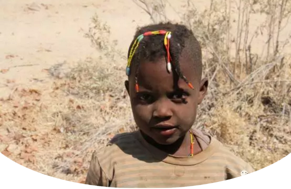 　　库内内，位于纳米比亚西北部，是纳米比亚第十三个行政区，因库内内河而得名。库内内河也是纳米比亚与安哥拉的界河。库内内地区居住着辛巴族、达马拉族、赫雷罗等多个民族。辛巴族又称红泥族，因不洗澡，仅在全身涂抹红泥而得名。  　　我们驾车从首都温得和克出发，一路北上，在埃托沙国家公园住宿一晚。第二日，抵达纳米比亚与安哥拉的边境小镇，距离首都800公里的洛卡纳(Ruacana)。  　　由于正值旱季，库内内河上游河水被水电站拦截，这里的洛卡纳瀑布仅有几支细流穿过岩石，堙没于谷底的乱石杂草中。从洛卡纳沿着库内内河一路向东，要在天黑前入住库内内河旅社。  　　    　　库内内河两岸风光。  　　河岸边的山间道路十分难走，我们以每小时30、40公里的速度前行。坑坑洼洼的土路只有四驱车或SUV才行。  　　天色越来越暗了，由于道路难行，已经无法在日落前赶到旅店。又赶上导航仪时常丢信号，几次走了错路。路上遇到一潭积水，不知道水的深浅，又不是四驱车，我们不敢贸然前行。  　　围着绕了几圈，都没有找到路。此时天已经完全黑了下来，我们前不着村，后不着店，心里不禁涌起一阵恐惧。  　　这时不知从何处，跑来一群红泥人孩子，司机请他们指路。于是，孩子们在前面奔跑，我们开车在后面尾随。翻过几个山坡儿、驶过几个急转弯儿，总算是绕过了泥潭。停下车子，其中一个年长的孩子，指着自己和他们的伙伴们，数着，“1，2，3，4，5，6。”我把随行带来的糖果、零食分给他们。孩子们很高兴，挥手道别。  　　    　　伊普帕瀑布边的当地儿童。  　　又走了将近半个小时，终于抵达了落脚旅店，人已被颠簸地七零八落，脑子沉沉，只希望明天的路能好走些。  　　第二天继续沿库内内河向西行驶，向一百多公里外伊普帕(Epupa)瀑布的方向前行。路过一条干涸的河床。沙子早已淹没了河床。不是四驱车的弊端再次显现，车子刚冲进河床边缘就沦陷了。好在有辛巴族的两个壮年小伙儿路过，帮助我们将车子从沙床里推了出去。过了沙地，前面的路依然难行，几次我都感觉车子走在悬崖峭壁上，心提到嗓子眼儿，又不敢大叫出来。生怕影响司机驾驶。  　　一路向西，沿途路过很多辛巴族人的村子。所谓村子，不过是用柴草围建的几间小屋，再用篱笆把这些柴草屋圈起来罢了。透过木头间的缝隙，窥视屋内，比家徒四壁还要家徒四壁。辛巴族人的所有财产就是那山间里放养的牛和羊了。  　　路上遇到很多辛巴族的孩子，老远地向我们打招呼。每每司机也会到跟前踩脚刹车，我则把事前准备好的糖果、零食分给这些孩子。孩子们像拿了圣诞礼物一样，说着“Thank you”跑开了。  　　    　　辛巴族孩子看不出性别，以额前束发进行区分，前面扎两个小辫子的是女孩，一个小辫子的是男儿。随着时代的变迁，辛巴族人与现代社会慢慢接轨，装束上也有很大的改变。  　　在几个村落之间，人口相对密集的地方会有小学、卫生站以及政府行政部门。要识别这些建筑也很简单，因为这些房子是全村或全镇最好的房子。学校一般是红色砖墙，个别的还有玻璃窗户。卫生站会有醒目的十字标识，墙上写着clinic或health等字样。而政府行政单位，则一般会挂着国旗。  　　在乡路上行驶，偶尔会看到“THE EDCUATION IS GREATER THAN LESS”一类的大字标语，类似于我国农村的“要想富，少生孩子多种树”。  　　    　　伊普帕瀑布景观。  　　正午时分终于到达目的地伊普帕瀑布。瀑布完全没有想象中的壮观。不过相比洛卡纳瀑布，起码还有水可看。司机说，“不来过，怎么知道呢。要学会随遇而安。这就是自然啊!”  　　文章来自：新华非洲