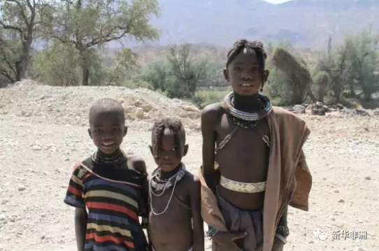 　　库内内，位于纳米比亚西北部，是纳米比亚第十三个行政区，因库内内河而得名。库内内河也是纳米比亚与安哥拉的界河。库内内地区居住着辛巴族、达马拉族、赫雷罗等多个民族。辛巴族又称红泥族，因不洗澡，仅在全身涂抹红泥而得名。  　　我们驾车从首都温得和克出发，一路北上，在埃托沙国家公园住宿一晚。第二日，抵达纳米比亚与安哥拉的边境小镇，距离首都800公里的洛卡纳(Ruacana)。  　　由于正值旱季，库内内河上游河水被水电站拦截，这里的洛卡纳瀑布仅有几支细流穿过岩石，堙没于谷底的乱石杂草中。从洛卡纳沿着库内内河一路向东，要在天黑前入住库内内河旅社。  　　    　　库内内河两岸风光。  　　河岸边的山间道路十分难走，我们以每小时30、40公里的速度前行。坑坑洼洼的土路只有四驱车或SUV才行。  　　天色越来越暗了，由于道路难行，已经无法在日落前赶到旅店。又赶上导航仪时常丢信号，几次走了错路。路上遇到一潭积水，不知道水的深浅，又不是四驱车，我们不敢贸然前行。  　　围着绕了几圈，都没有找到路。此时天已经完全黑了下来，我们前不着村，后不着店，心里不禁涌起一阵恐惧。  　　这时不知从何处，跑来一群红泥人孩子，司机请他们指路。于是，孩子们在前面奔跑，我们开车在后面尾随。翻过几个山坡儿、驶过几个急转弯儿，总算是绕过了泥潭。停下车子，其中一个年长的孩子，指着自己和他们的伙伴们，数着，“1，2，3，4，5，6。”我把随行带来的糖果、零食分给他们。孩子们很高兴，挥手道别。  　　    　　伊普帕瀑布边的当地儿童。  　　又走了将近半个小时，终于抵达了落脚旅店，人已被颠簸地七零八落，脑子沉沉，只希望明天的路能好走些。  　　第二天继续沿库内内河向西行驶，向一百多公里外伊普帕(Epupa)瀑布的方向前行。路过一条干涸的河床。沙子早已淹没了河床。不是四驱车的弊端再次显现，车子刚冲进河床边缘就沦陷了。好在有辛巴族的两个壮年小伙儿路过，帮助我们将车子从沙床里推了出去。过了沙地，前面的路依然难行，几次我都感觉车子走在悬崖峭壁上，心提到嗓子眼儿，又不敢大叫出来。生怕影响司机驾驶。  　　一路向西，沿途路过很多辛巴族人的村子。所谓村子，不过是用柴草围建的几间小屋，再用篱笆把这些柴草屋圈起来罢了。透过木头间的缝隙，窥视屋内，比家徒四壁还要家徒四壁。辛巴族人的所有财产就是那山间里放养的牛和羊了。  　　路上遇到很多辛巴族的孩子，老远地向我们打招呼。每每司机也会到跟前踩脚刹车，我则把事前准备好的糖果、零食分给这些孩子。孩子们像拿了圣诞礼物一样，说着“Thank you”跑开了。  　　    　　辛巴族孩子看不出性别，以额前束发进行区分，前面扎两个小辫子的是女孩，一个小辫子的是男儿。随着时代的变迁，辛巴族人与现代社会慢慢接轨，装束上也有很大的改变。  　　在几个村落之间，人口相对密集的地方会有小学、卫生站以及政府行政部门。要识别这些建筑也很简单，因为这些房子是全村或全镇最好的房子。学校一般是红色砖墙，个别的还有玻璃窗户。卫生站会有醒目的十字标识，墙上写着clinic或health等字样。而政府行政单位，则一般会挂着国旗。  　　在乡路上行驶，偶尔会看到“THE EDCUATION IS GREATER THAN LESS”一类的大字标语，类似于我国农村的“要想富，少生孩子多种树”。  　　    　　伊普帕瀑布景观。  　　正午时分终于到达目的地伊普帕瀑布。瀑布完全没有想象中的壮观。不过相比洛卡纳瀑布，起码还有水可看。司机说，“不来过，怎么知道呢。要学会随遇而安。这就是自然啊!”  　　文章来自：新华非洲