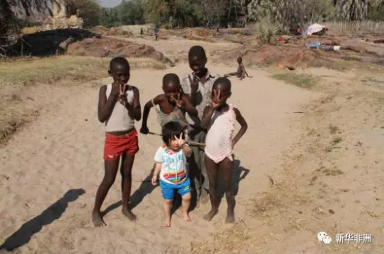 　　库内内，位于纳米比亚西北部，是纳米比亚第十三个行政区，因库内内河而得名。库内内河也是纳米比亚与安哥拉的界河。库内内地区居住着辛巴族、达马拉族、赫雷罗等多个民族。辛巴族又称红泥族，因不洗澡，仅在全身涂抹红泥而得名。  　　我们驾车从首都温得和克出发，一路北上，在埃托沙国家公园住宿一晚。第二日，抵达纳米比亚与安哥拉的边境小镇，距离首都800公里的洛卡纳(Ruacana)。  　　由于正值旱季，库内内河上游河水被水电站拦截，这里的洛卡纳瀑布仅有几支细流穿过岩石，堙没于谷底的乱石杂草中。从洛卡纳沿着库内内河一路向东，要在天黑前入住库内内河旅社。  　　    　　库内内河两岸风光。  　　河岸边的山间道路十分难走，我们以每小时30、40公里的速度前行。坑坑洼洼的土路只有四驱车或SUV才行。  　　天色越来越暗了，由于道路难行，已经无法在日落前赶到旅店。又赶上导航仪时常丢信号，几次走了错路。路上遇到一潭积水，不知道水的深浅，又不是四驱车，我们不敢贸然前行。  　　围着绕了几圈，都没有找到路。此时天已经完全黑了下来，我们前不着村，后不着店，心里不禁涌起一阵恐惧。  　　这时不知从何处，跑来一群红泥人孩子，司机请他们指路。于是，孩子们在前面奔跑，我们开车在后面尾随。翻过几个山坡儿、驶过几个急转弯儿，总算是绕过了泥潭。停下车子，其中一个年长的孩子，指着自己和他们的伙伴们，数着，“1，2，3，4，5，6。”我把随行带来的糖果、零食分给他们。孩子们很高兴，挥手道别。  　　    　　伊普帕瀑布边的当地儿童。  　　又走了将近半个小时，终于抵达了落脚旅店，人已被颠簸地七零八落，脑子沉沉，只希望明天的路能好走些。  　　第二天继续沿库内内河向西行驶，向一百多公里外伊普帕(Epupa)瀑布的方向前行。路过一条干涸的河床。沙子早已淹没了河床。不是四驱车的弊端再次显现，车子刚冲进河床边缘就沦陷了。好在有辛巴族的两个壮年小伙儿路过，帮助我们将车子从沙床里推了出去。过了沙地，前面的路依然难行，几次我都感觉车子走在悬崖峭壁上，心提到嗓子眼儿，又不敢大叫出来。生怕影响司机驾驶。  　　一路向西，沿途路过很多辛巴族人的村子。所谓村子，不过是用柴草围建的几间小屋，再用篱笆把这些柴草屋圈起来罢了。透过木头间的缝隙，窥视屋内，比家徒四壁还要家徒四壁。辛巴族人的所有财产就是那山间里放养的牛和羊了。  　　路上遇到很多辛巴族的孩子，老远地向我们打招呼。每每司机也会到跟前踩脚刹车，我则把事前准备好的糖果、零食分给这些孩子。孩子们像拿了圣诞礼物一样，说着“Thank you”跑开了。  　　    　　辛巴族孩子看不出性别，以额前束发进行区分，前面扎两个小辫子的是女孩，一个小辫子的是男儿。随着时代的变迁，辛巴族人与现代社会慢慢接轨，装束上也有很大的改变。  　　在几个村落之间，人口相对密集的地方会有小学、卫生站以及政府行政部门。要识别这些建筑也很简单，因为这些房子是全村或全镇最好的房子。学校一般是红色砖墙，个别的还有玻璃窗户。卫生站会有醒目的十字标识，墙上写着clinic或health等字样。而政府行政单位，则一般会挂着国旗。  　　在乡路上行驶，偶尔会看到“THE EDCUATION IS GREATER THAN LESS”一类的大字标语，类似于我国农村的“要想富，少生孩子多种树”。  　　    　　伊普帕瀑布景观。  　　正午时分终于到达目的地伊普帕瀑布。瀑布完全没有想象中的壮观。不过相比洛卡纳瀑布，起码还有水可看。司机说，“不来过，怎么知道呢。要学会随遇而安。这就是自然啊!”  　　文章来自：新华非洲